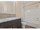 Bathroom with a shower-tub combo, dark wood cabinets, and a tile backsplash at 406 Stewart Town Rd, Lillington, NC 27546
