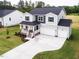 Charming two-story home with gray siding, blue shutters, covered porch, and three-car garage at 456 Barbour Farm Ln, Four Oaks, NC 27524