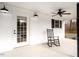 Close-up view of a covered porch with classic rocking chair next to white door at 4664 Quarter Creek Ln, Liberty, NC 27298