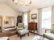 Cozy living room showcasing hardwood floors, a comfortable armchair, and windows draped with elegant curtains at 6609 Mountain Brook Ln, Raleigh, NC 27615