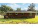 A cozy brick home with a dark roof and several windows, with green grass, and mature trees in the backyard at 702 Joyner St, Clayton, NC 27520