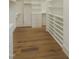 Spacious walk-in closet featuring built-in shelving, drawers, and hardwood flooring at 7723 Roberts Rd, Apex, NC 27523