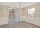 Dining room with a chandelier, gray flooring, white wainscoting, and sliding glass door access to backyard at 912 Obsidian Way, Durham, NC 27703