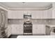 Modern kitchen with white cabinetry, stainless steel appliances and gray subway tile backsplash at 912 Obsidian Way, Durham, NC 27703