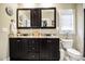 Bathroom with granite countertops, dark cabinetry, dual mirrors, toilet, and decorative accents at 103 Bella Sq Sq, Smithfield, NC 27577