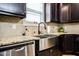 Close-up of kitchen sink with stainless steel appliances, granite countertops and dark cabinets at 103 Bella Sq Sq, Smithfield, NC 27577