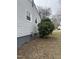 Side view of home with gray siding, showcasing the gas meter and a lush green bush at 104 N Garden Ave, Siler City, NC 27344