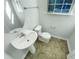 A small, windowed half-bath with a pedestal sink and a standard toilet and vinyl floor at 1424 Elk Falls Dr, Wendell, NC 27591