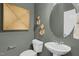 Well-lit powder room with a round mirror and decorative wall art at 144 Kobus Ct, Garner, NC 27529