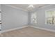 Bright bedroom with neutral carpet, soft gray walls, white trim, and natural light from two windows at 198 Gentry Dr, Pittsboro, NC 27312