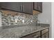 Close-up of a kitchen featuring granite countertops and a mosaic tile backsplash, offering a modern and stylish design at 198 Gentry Dr, Pittsboro, NC 27312
