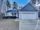 Charming home featuring a two-car garage, blue shingle accents, light gray siding, and well-manicured landscaping at 201 Silver Creek Dr, Clayton, NC 27520