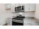 Well-equipped kitchen featuring stainless steel appliances, granite countertops, and gray cabinets at 208 Starlight St, Sanford, NC 27330
