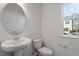 Well-lit powder room featuring a pedestal sink and round mirror at 260 Chesapeake Commons St # 156, Garner, NC 27529