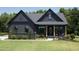 Charming home featuring a dark exterior, well-manicured lawn, and a welcoming front porch with wooden pillars at 306 Golden Leaf Farms Rd, Angier, NC 27501