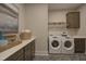 Functional laundry room with modern washer and dryer, ample counter space, and storage cabinets at 306 Golden Leaf Farms Rd, Angier, NC 27501