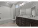 Bathroom features a double sink vanity with dark cabinets, neutral tile floor, and bathtub with white tile surround at 35 Wheatfield Ln, Youngsville, NC 27596