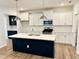 New kitchen features a dark island, white cabinets, stainless steel appliances, and quartz countertops at 62 Blue Iris Pkwy # 125, Clayton, NC 27520