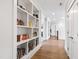 Hallway with hardwood floors, bright lighting, white trim, and a large built-in bookcase at 7212 Summer Tanager Trl, Raleigh, NC 27614