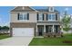 Two-story home featuring brick and siding, a two-car garage, and a charming covered front porch at 168 Paper Birch Way, Fuquay Varina, NC 27526
