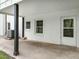 Back porch with gray concrete flooring and white brick walls, door and dual windows at 206 Ellington Rd, Graham, NC 27253