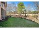 Green backyard with a sitting area, surrounded by a black fence and mature trees at 2933 Elmfield St, Raleigh, NC 27614