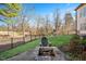 Cozy backyard area with a stone fire pit, iron fence, and view of the wooded area beyond at 2933 Elmfield St, Raleigh, NC 27614