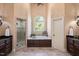 Bright primary bathroom featuring double sinks, a separate glass shower, and a soaking tub beneath an arched window at 2933 Elmfield St, Raleigh, NC 27614