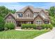 Stately stone-and-siding home featuring lush landscaping, a manicured lawn, and a covered porch at 2933 Elmfield St, Raleigh, NC 27614