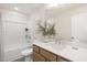 Bathroom featuring wood cabinets, quartz countertop, framed mirror, and tub with white tile surround at 344 Church St, Morrisville, NC 27560