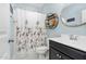 Bathroom with a black vanity, round mirror, and a shower-tub combo with a patterned curtain at 132 Mystic Pine Pl, Apex, NC 27539