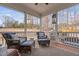 Screened porch with wicker chairs and foot rests, with a view of the backyard and fireplace at 132 Mystic Pine Pl, Apex, NC 27539