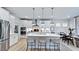 A modern kitchen features white cabinets, stainless steel appliances, an island, and pendant lighting at 249 Tidal Pool Way, Cary, NC 27513