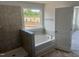 Bright bathroom featuring a soaking tub with tiled surround and window view at 249 Tidal Pool Way, Cary, NC 27519