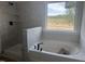 Bright bathroom featuring a soaking tub, tiled shower, and a large window with a wooded view at 253 Tidal Pool Way, Cary, NC 27519