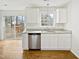 Well-lit kitchen featuring white cabinets, granite countertops, stainless steel dishwasher, and hardwood flooring at 3604 Tunas St, Raleigh, NC 27616