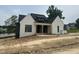Newly built home with a white painted brick facade, dark roof, and wood porch posts, creating a modern farmhouse appeal at 395 Meadow Walk Dr, Fuquay Varina, NC 27526