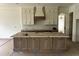 Spacious kitchen island featuring modern cabinetry and hardware, complemented by custom hood vent and upper cabinets at 395 Meadow Walk Dr, Fuquay Varina, NC 27526