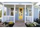 Close-up of the light blue home with white trim and a yellow front door framed by a tidy porch at 518 Worth St, Raleigh, NC 27601