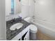 This white bathroom features a granite countertop and a shower-tub combo at 6423 Whitt Rd, Durham, NC 27712