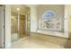 Bright bathroom featuring a glass shower, tub under an arched window, and tile floors at 1013 Timber Mist Ct, Cary, NC 27519