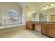 Bright bathroom showcasing a tub under a window, a wooden vanity, and tile floors at 1013 Timber Mist Ct, Cary, NC 27519