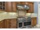 Gourmet kitchen featuring stainless steel appliances, a range hood, and custom wood cabinetry at 1013 Timber Mist Ct, Cary, NC 27519