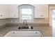 A kitchen sink with granite countertops and white cabinets under a window at 104 Eddy Ct, Benson, NC 27504