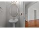 Cozy half-bathroom with pedestal sink and oval mirror, conveniently located near the entryway at 11425 Shadow Elms Ln, Raleigh, NC 27614