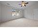 Spacious bedroom with neutral walls, carpet, ceiling fan, and bright window overlooking the neighborhood at 11425 Shadow Elms Ln, Raleigh, NC 27614