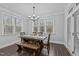 Dining area with a rustic wood table, bench seating, a modern chandelier, and natural light from windows at 130 Willow Bend Dr, Youngsville, NC 27596