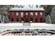 Stunning two-story brick home featuring a symmetrical facade, wreaths, and snow-covered landscaping at 1612 Hunting Ridge Rd, Raleigh, NC 27615