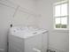 Well-lit laundry room with modern white washer and dryer, shelving, and classic black and white patterned flooring at 249 Beacon Dr, Pittsboro, NC 27312