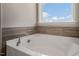 Modern white soaking tub with tile surround under a bright window at 326 Umstead St, Sanford, NC 27330